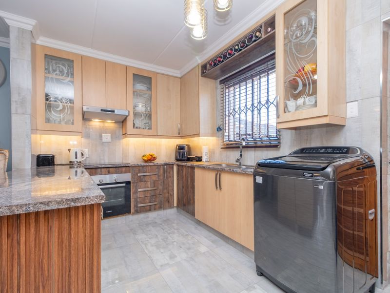 A well-appointed kitchen featuring granite countertops, built-in oven, extractor fan, under-cabinet lighting, and ample cabinetry with integrated wine storage.