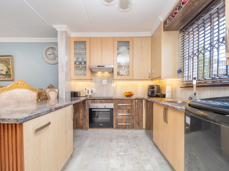 A well-maintained kitchen featuring light wood cabinetry, granite countertops, built-in oven, extractor fan, and under-cabinet lighting, providing a functional and organized cooking space.