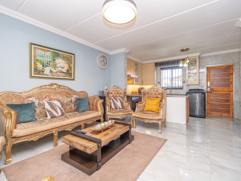 Open-plan living area featuring tiled flooring, coved ceilings, and a functional kitchen with built-in cabinetry and appliances.