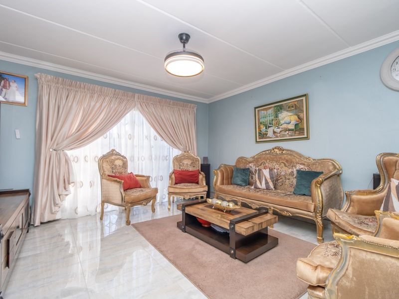 A well-maintained living room featuring polished tiled flooring, a central ceiling fan, and large sliding glass doors that provide ample natural light.