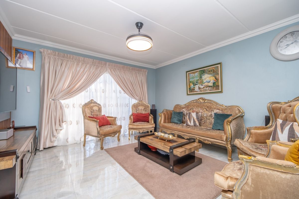 A well-maintained living room featuring polished tiled flooring, a central ceiling fan, and large sliding glass doors that provide ample natural light.