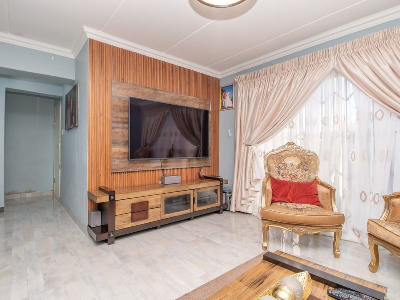 Living room featuring a timber slat feature wall, tiled flooring, and coved ceiling cornice, providing a functional space for relaxation.