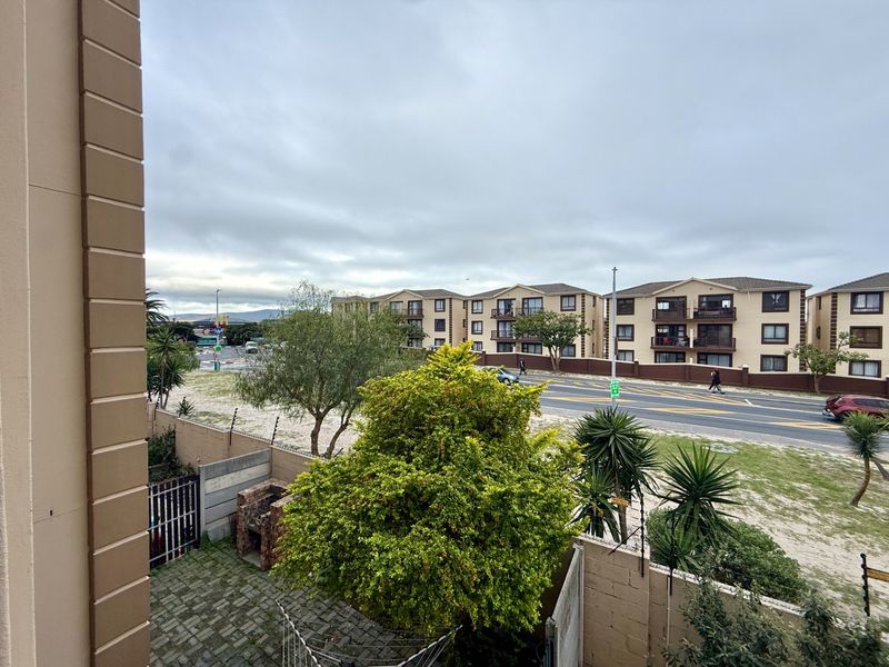 An elevated view overlooking a street, neighbouring apartment complex, and a small private courtyard area with a built-in braai.