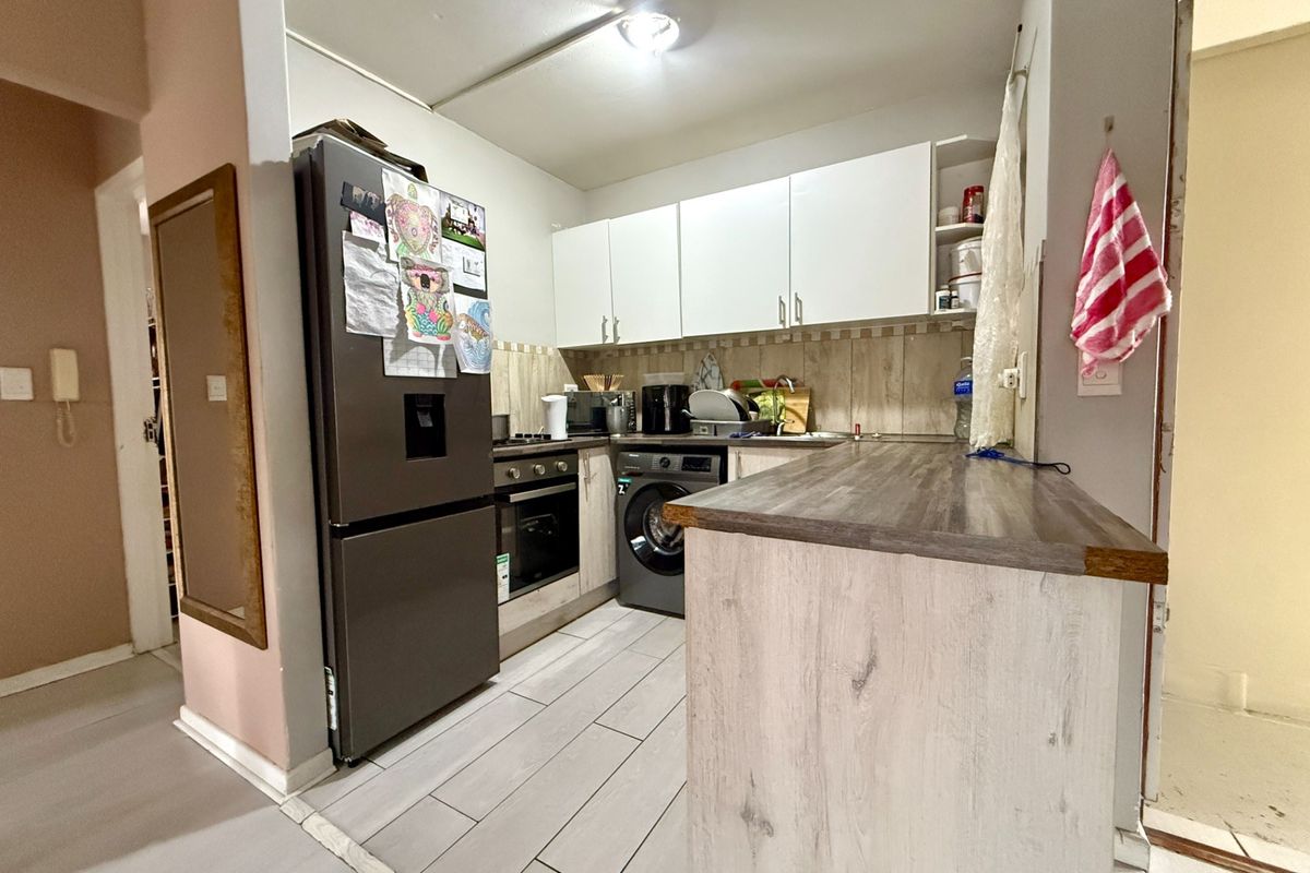Compact kitchen featuring white cabinetry, wood-look laminate countertops, tiled backsplash, and integrated oven with hob, providing a functional cooking space.