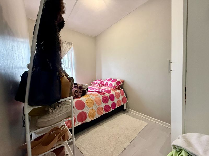 A compact bedroom featuring neutral wall finishes and a built-in cupboard, providing functional storage space within the apartment.