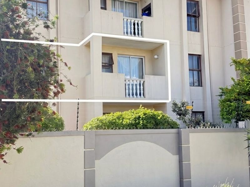 Exterior view of a multi-story apartment building featuring private balconies with sliding doors and a secure perimeter wall with electric fencing.