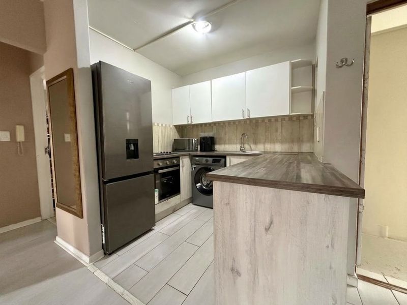 Compact kitchen featuring modern cabinetry, laminate countertops, tiled backsplash, and integrated appliances, offering a functional and efficient workspace.