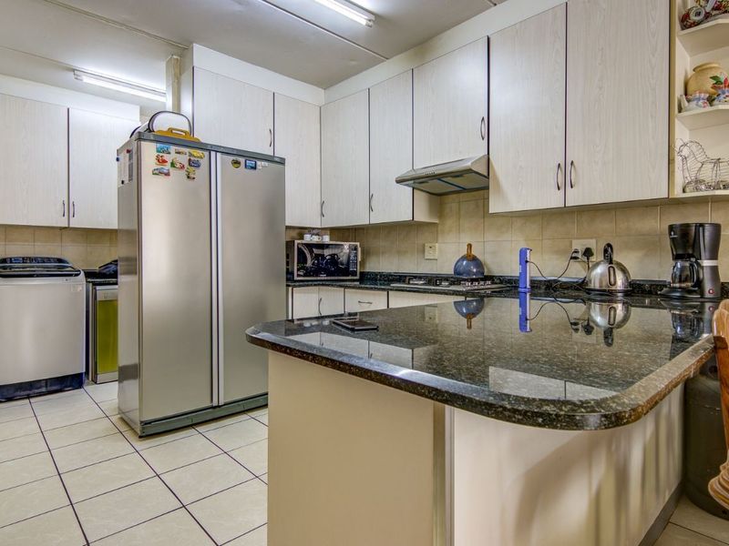 Functional kitchen featuring granite countertops, ample laminate cabinetry, tiled backsplash, and a convenient breakfast bar, providing a practical layout for daily meal preparation.