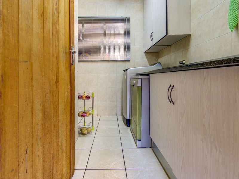 A functional laundry area featuring built-in cabinetry, tiled walls and flooring, and a solid wood door entrance.