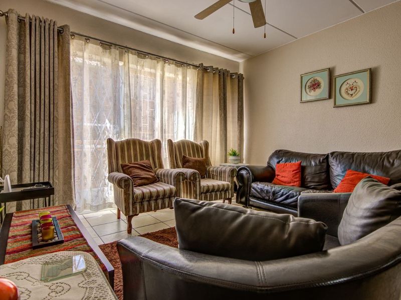 A comfortable living room featuring tiled flooring, a ceiling fan, and a large sliding glass door that provides natural light.