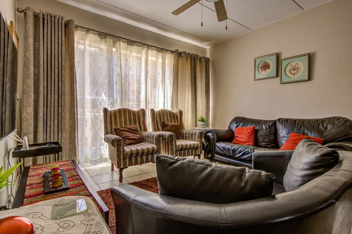 A comfortable living room featuring tiled flooring, a ceiling fan, and a large sliding glass door that provides natural light.