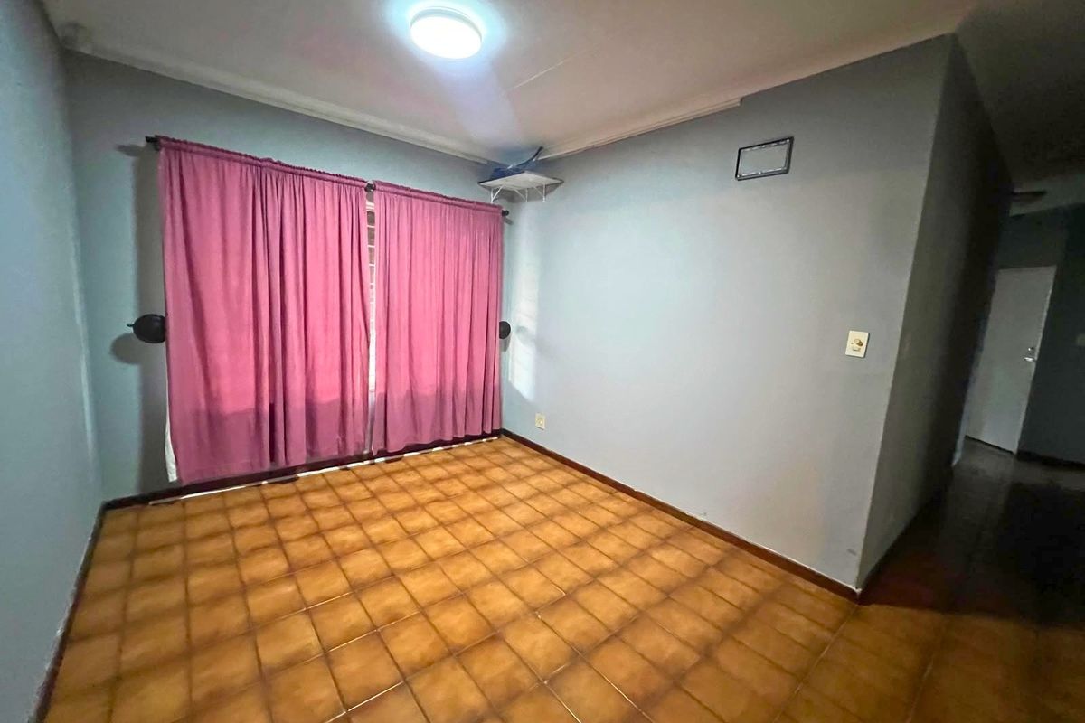 An empty bedroom featuring tiled flooring, neutral wall paint, and a ceiling light fixture, offering a blank canvas for renovation or staging.