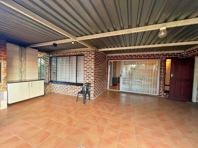 A covered outdoor patio featuring tiled flooring, a built-in serving counter with granite top, and direct access to the home through a sliding glass door.