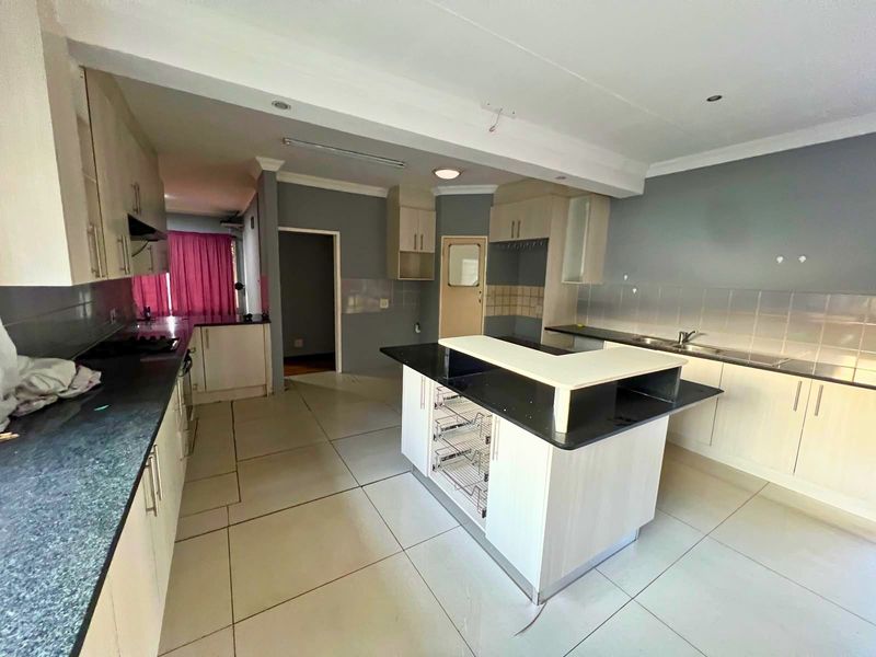 Spacious kitchen featuring a central island, ample built-in cabinetry, and tiled flooring, offering a functional layout ready for modern updates.