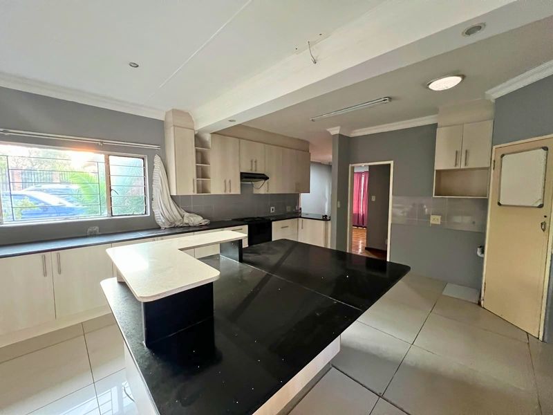 Spacious kitchen featuring light-toned cabinetry, black granite countertops, a breakfast nook, and tiled flooring, offering a functional layout ready for personalization.