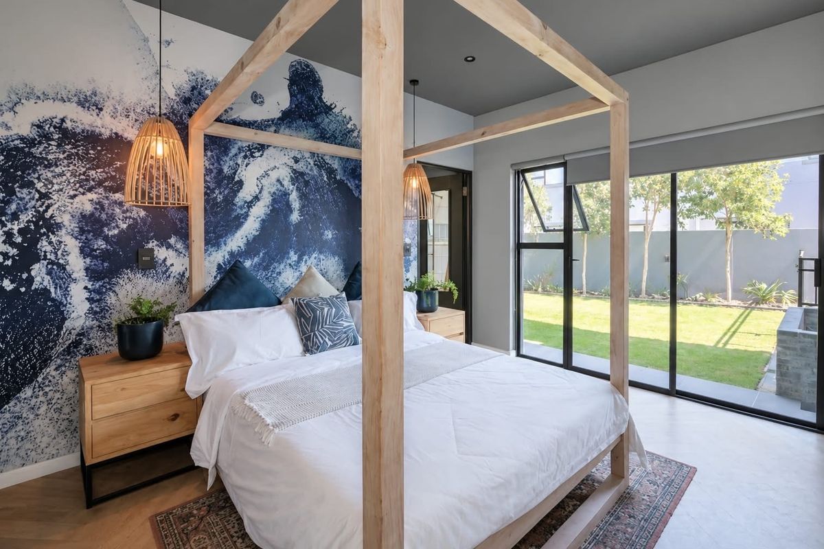 Modern bedroom featuring a striking feature wall, recessed lighting, and large sliding glass doors providing direct access to the rear garden.