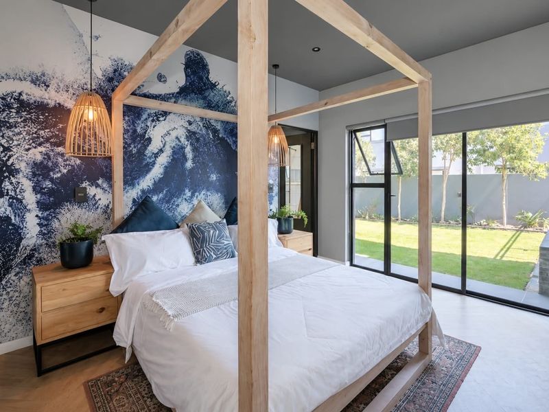 Modern bedroom featuring a striking feature wall, recessed lighting, and large sliding glass doors providing direct access to the rear garden.
