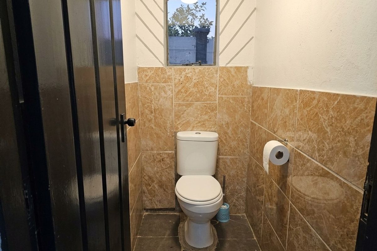 A compact guest bathroom featuring floor-to-ceiling marble-look wall tiles, dark floor tiles, and a standard white toilet.
