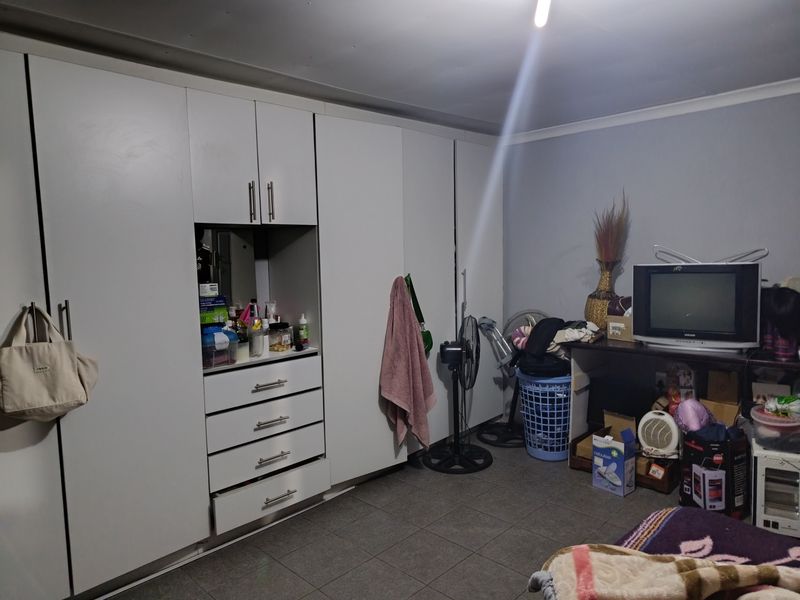 A bedroom featuring extensive white built-in cupboards with integrated drawers and tiled flooring.