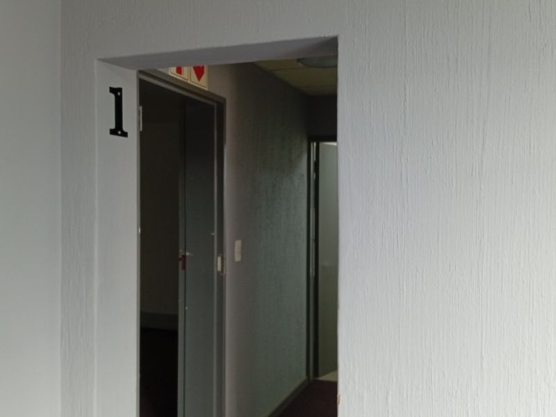 A view of a commercial hallway entrance marked with the number one, featuring textured walls and standard door frames.