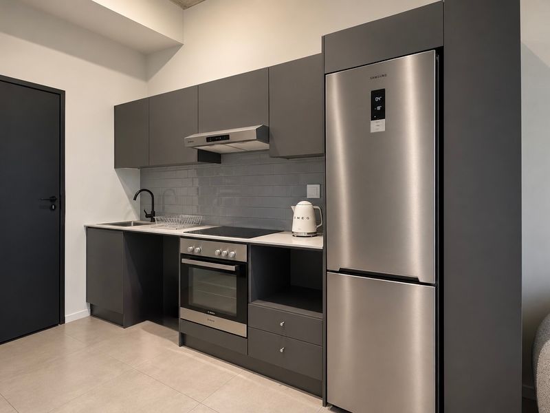 Modern kitchen featuring sleek dark grey cabinetry, subway tile backsplash, integrated stainless steel appliances, and high-quality matte black fixtures.