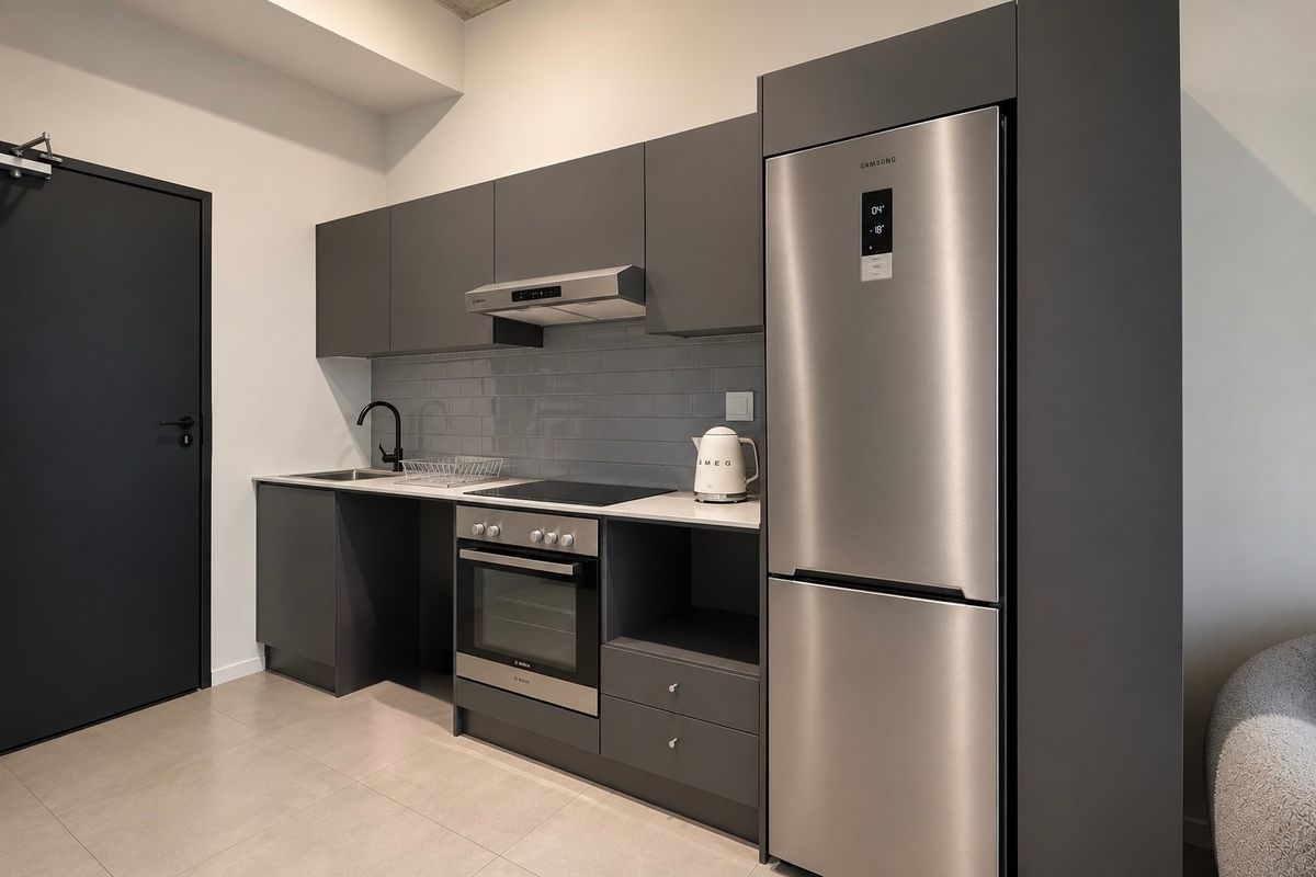 Modern kitchen featuring sleek dark grey cabinetry, subway tile backsplash, integrated stainless steel appliances, and high-quality matte black fixtures.
