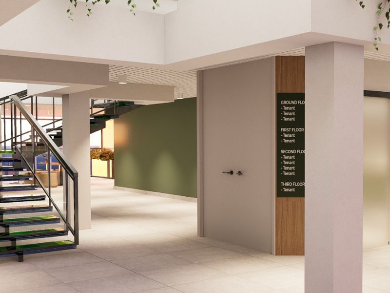 Modern commercial building lobby featuring a central staircase, tiled flooring, and a clear tenant directory signage board.