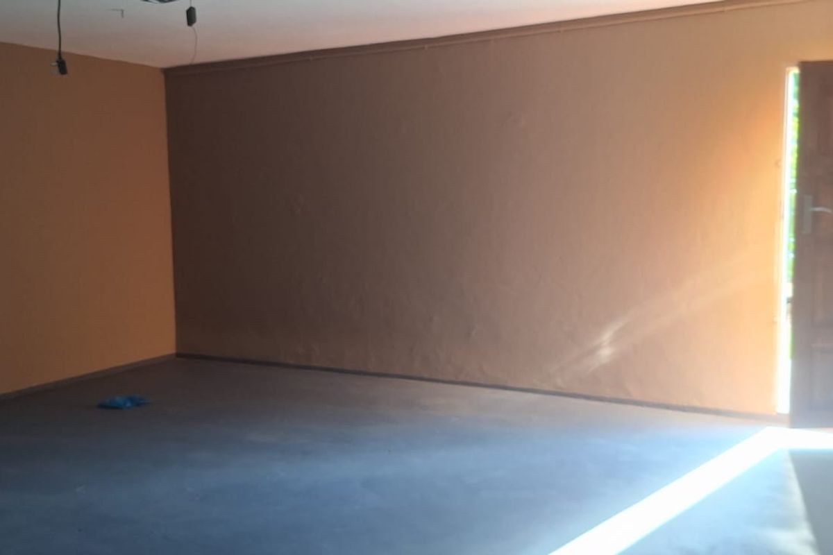 An empty, unfinished living area featuring a timber door and exposed electrical wiring, offering a blank canvas for renovation and interior design.