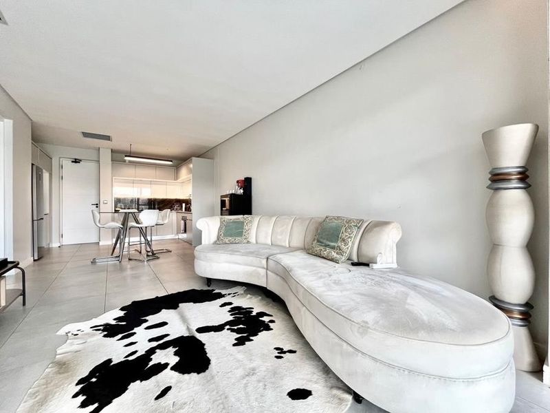 Modern open-plan living area featuring tiled flooring and a sleek, integrated kitchen with contemporary cabinetry.