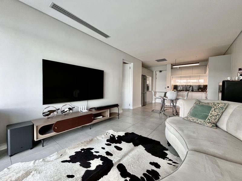 Modern open-plan living area featuring sleek tiled floors, ducted air conditioning, and a contemporary kitchen with integrated cabinetry.