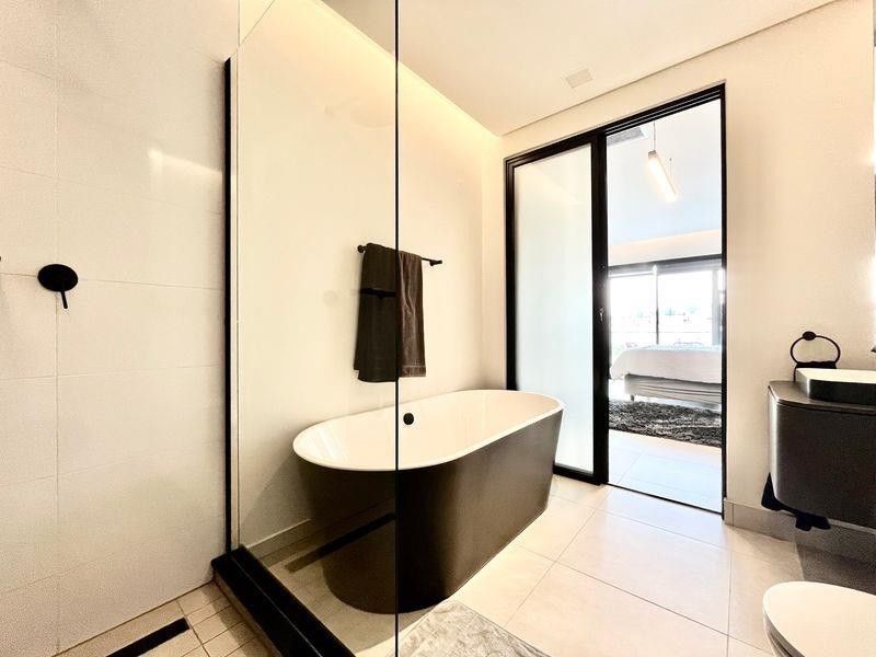 Modern bathroom featuring a sleek freestanding bathtub, glass-enclosed shower, and contemporary black fixtures with high-quality tiled finishes.
