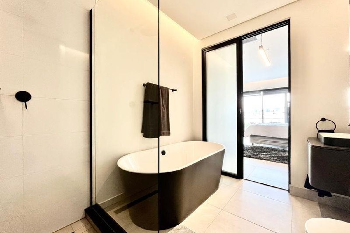 Modern bathroom featuring a sleek freestanding bathtub, glass-enclosed shower, and contemporary black fixtures with high-quality tiled finishes.