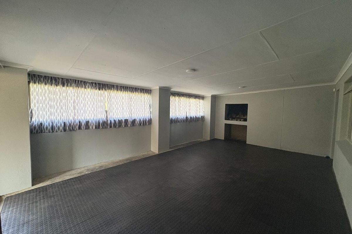 Spacious, empty living area featuring durable rubber flooring, a built-in fireplace, and ample natural light through multiple windows.