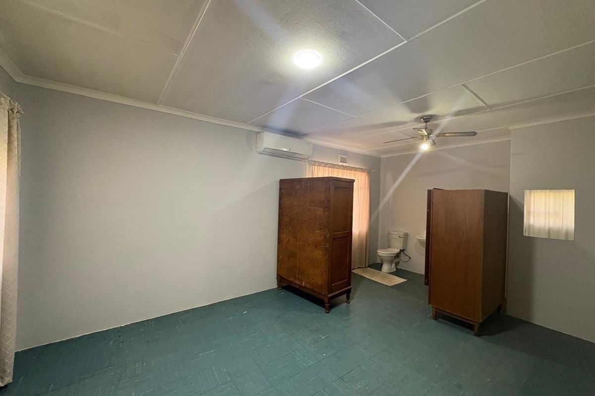 A bedroom featuring an integrated en-suite toilet and washbasin, equipped with a ceiling fan and split-system air conditioning unit.