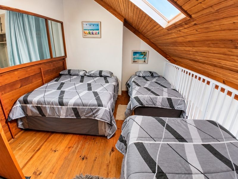 Loft-style bedroom featuring timber flooring, wood-paneled ceiling, and a skylight, providing a cozy and rustic atmosphere.