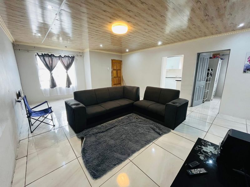 Spacious living room featuring glossy tiled flooring and a wood-look paneled ceiling, providing a neutral base for interior design updates.