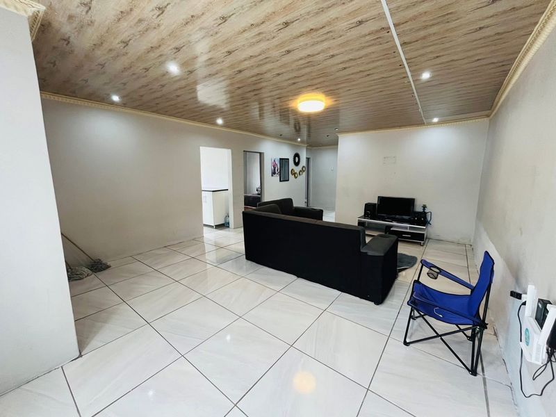 Spacious living area featuring large format floor tiles, wood-look ceiling paneling, and recessed lighting, offering a neutral base for interior design updates.
