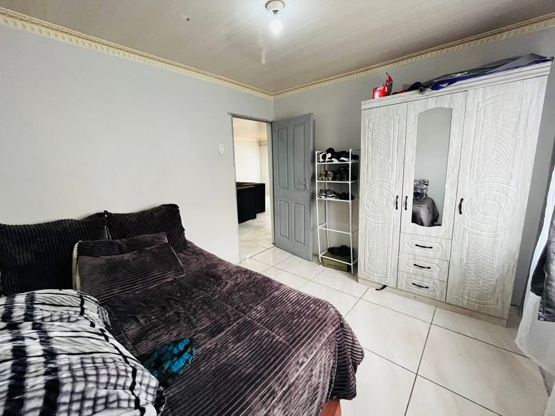 A bedroom featuring tiled flooring, crown molding, and a built-in wardrobe with a mirrored panel.