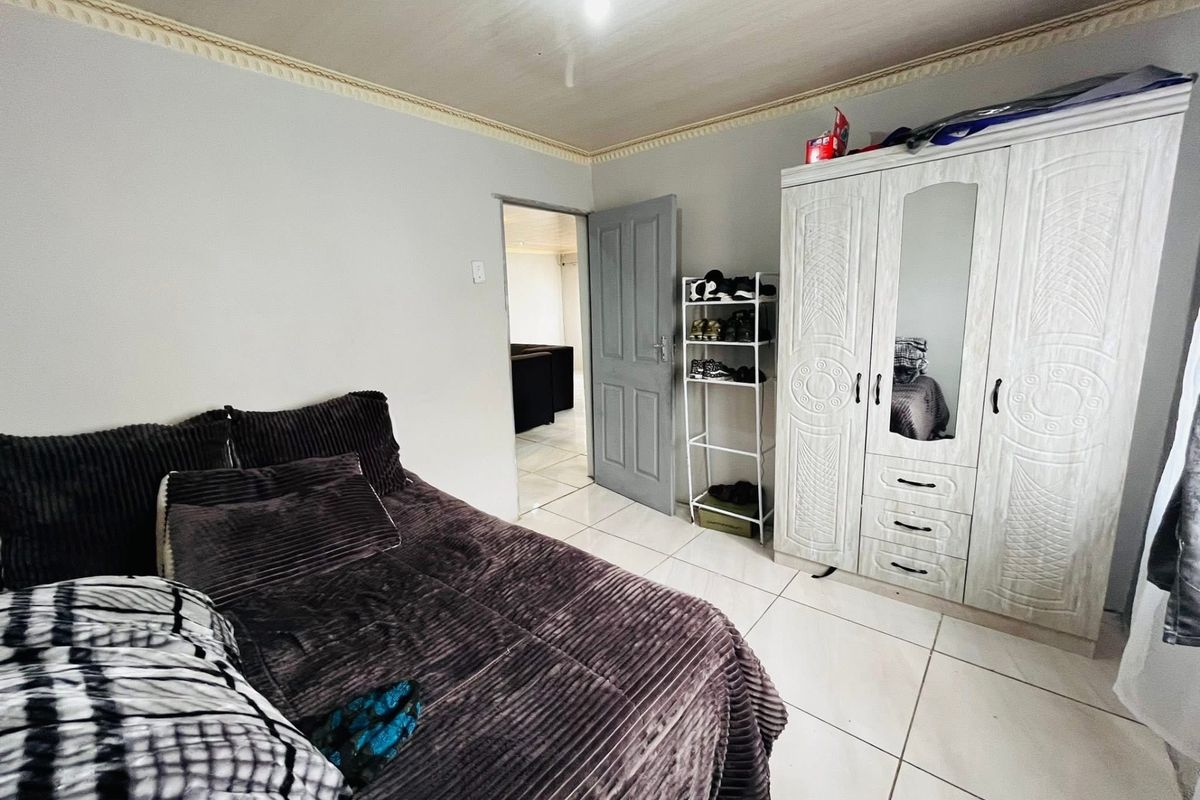 A bedroom featuring tiled flooring, crown molding, and a built-in wardrobe with a mirrored panel.