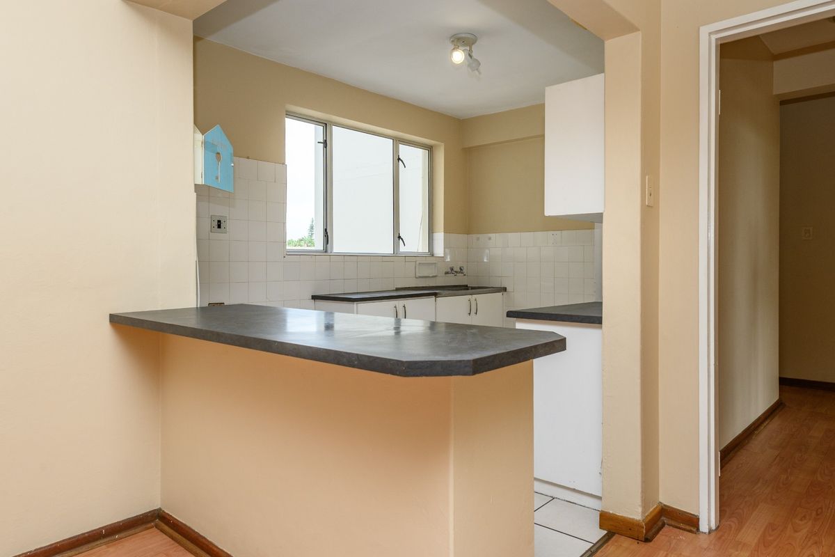 A functional kitchen featuring laminate countertops, a tiled backsplash, built-in cabinetry, and a convenient breakfast bar, offering a clean and practical layout.