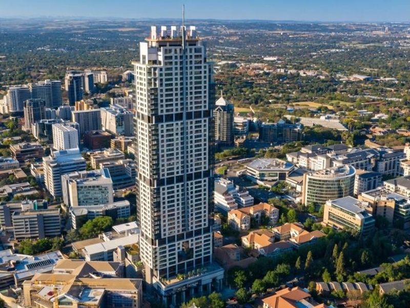 An aerial view of a prominent high-rise apartment building situated within a dense urban landscape.