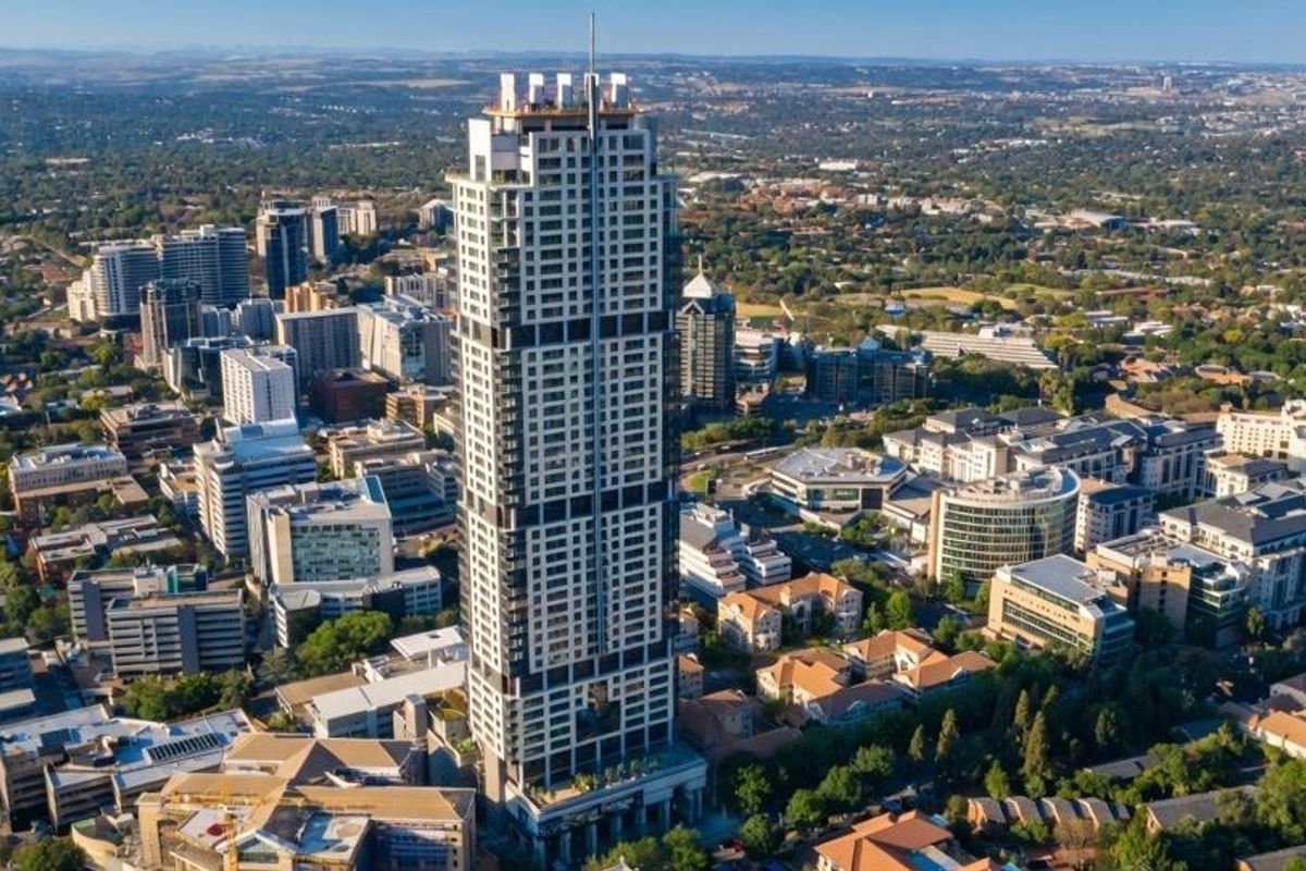 An aerial view of a prominent high-rise apartment building situated within a dense urban landscape.