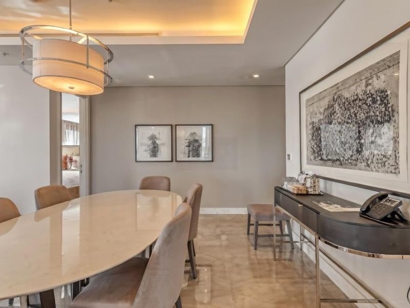 Elegant dining area featuring polished marble flooring, sophisticated cove lighting, and a modern pendant light fixture, creating a refined and welcoming atmosphere.