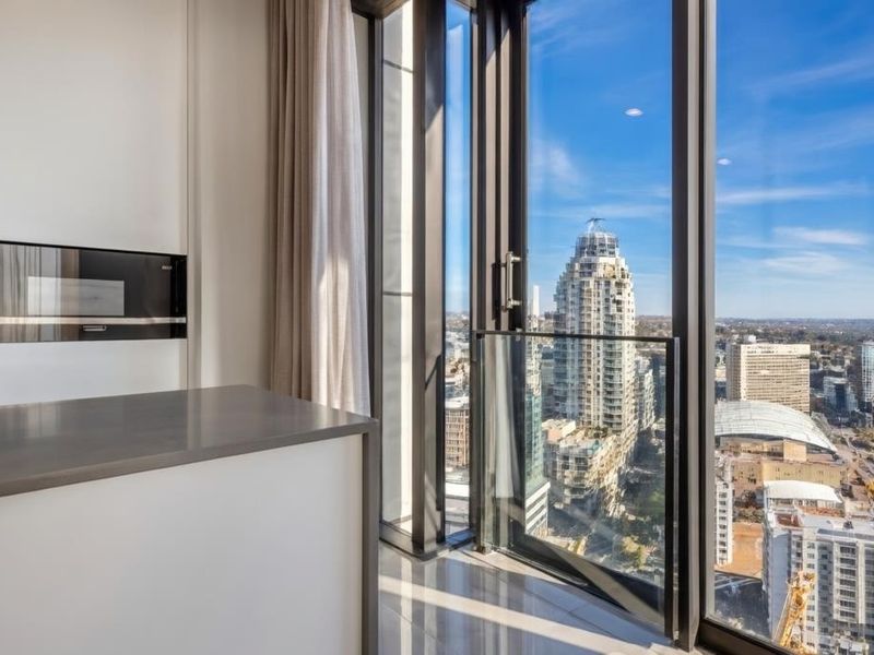 Modern open-plan living area featuring floor-to-ceiling windows with expansive city views, integrated microwave, and sleek stone countertops.
