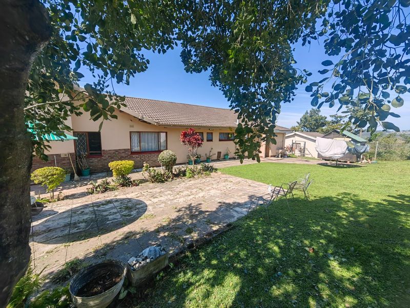 Rear view of the house featuring a paved patio area, established lawn, and brick-based exterior walls under a concrete tile roof.