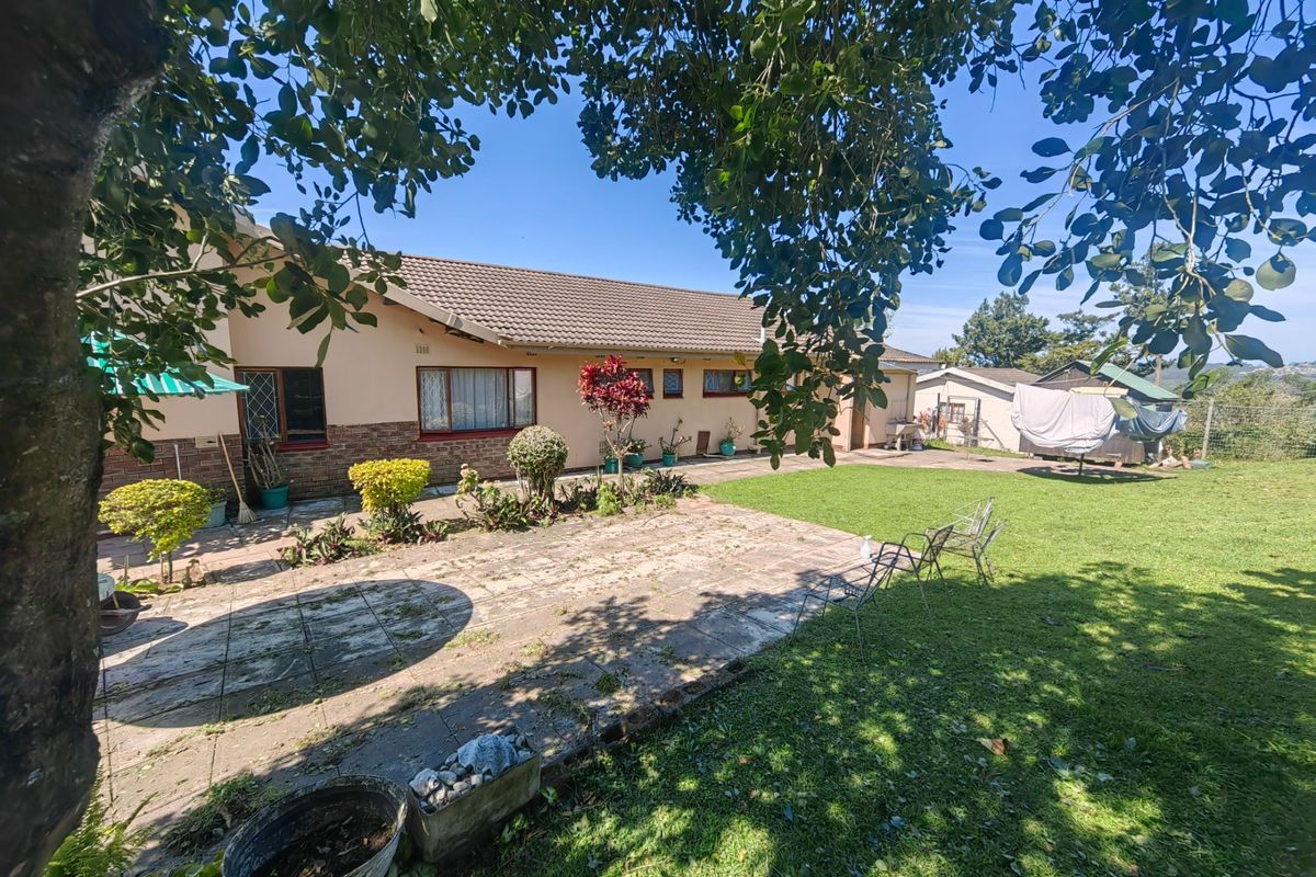 Rear view of the house featuring a paved patio area, established lawn, and brick-based exterior walls under a concrete tile roof.