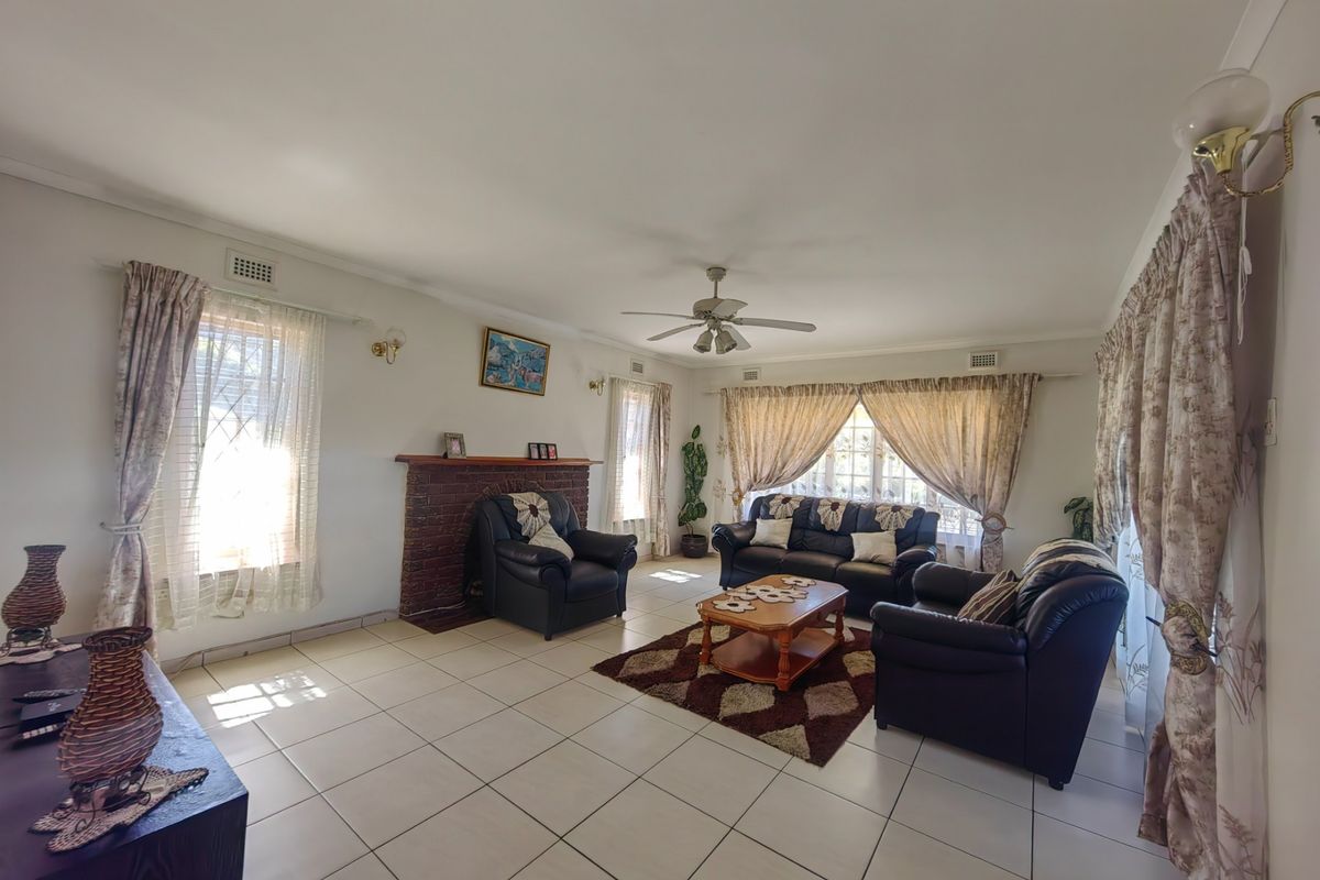 Spacious living room featuring tiled flooring, a brick fireplace, and a ceiling fan, offering a comfortable and functional layout.