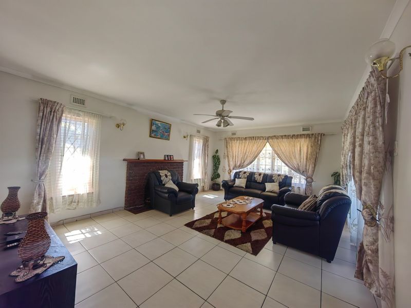 Spacious living room featuring tiled flooring, a brick fireplace, and a ceiling fan, offering a comfortable and functional layout.