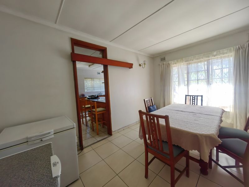 Dining area featuring tiled flooring and a view through to the kitchen, with natural light provided by a large window.