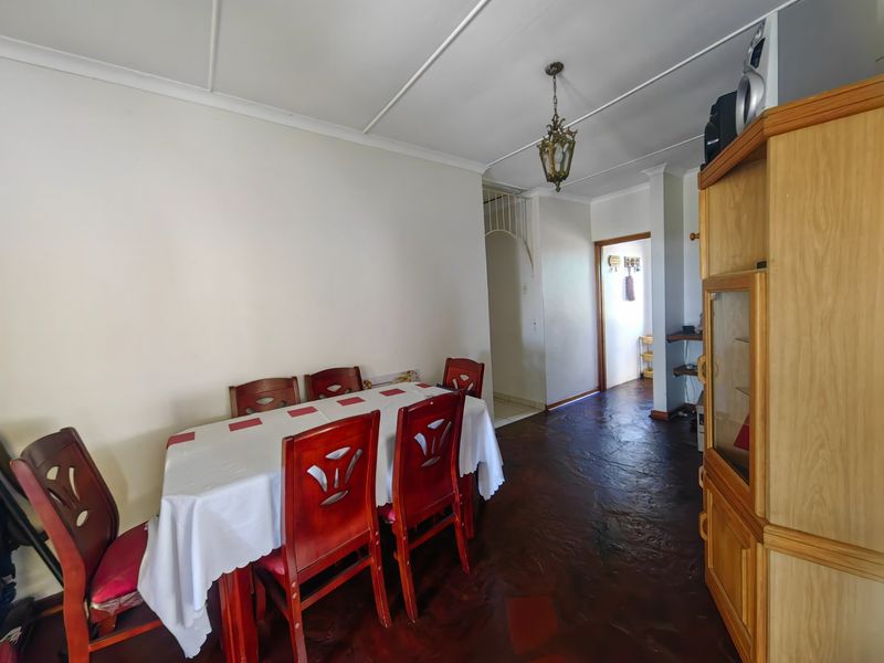 Dining area featuring traditional slate flooring, a classic pendant light fixture, and access to the hallway.